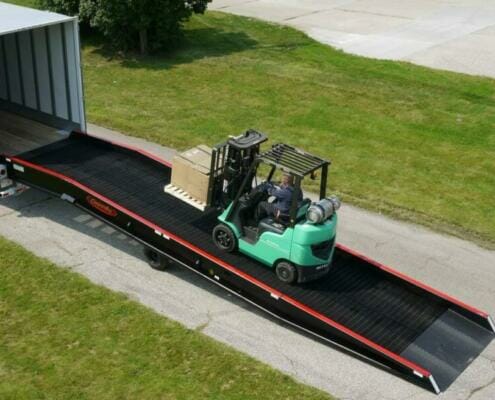 Green forklift carrying pallet towards semi truck on a heavy duty truck ramp | Heavy duty truck ramps by Copperloy